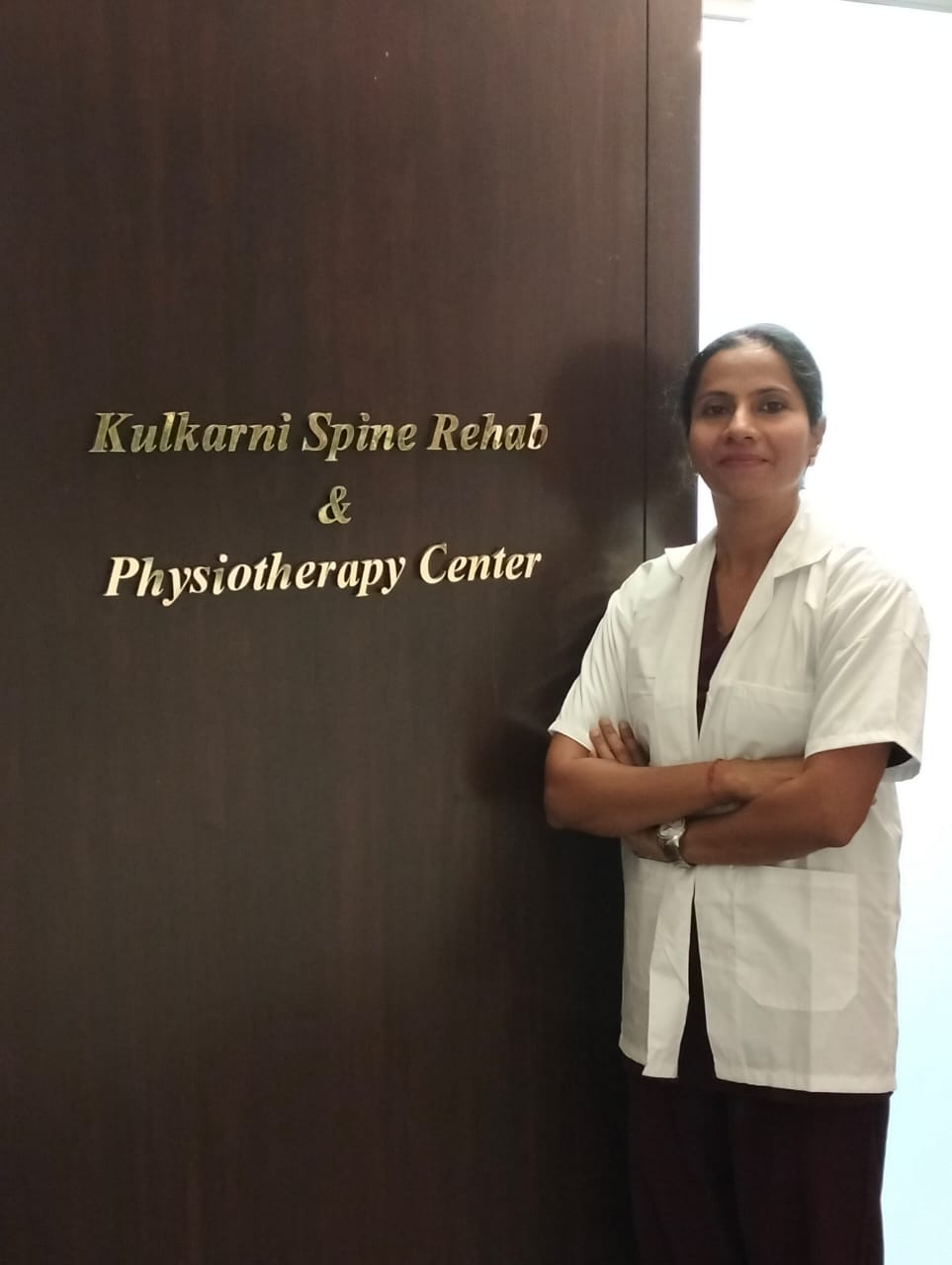 Dr. Chetna standing in front of the Kulkarni Spine Rehab & Physiotherapy Center office door.